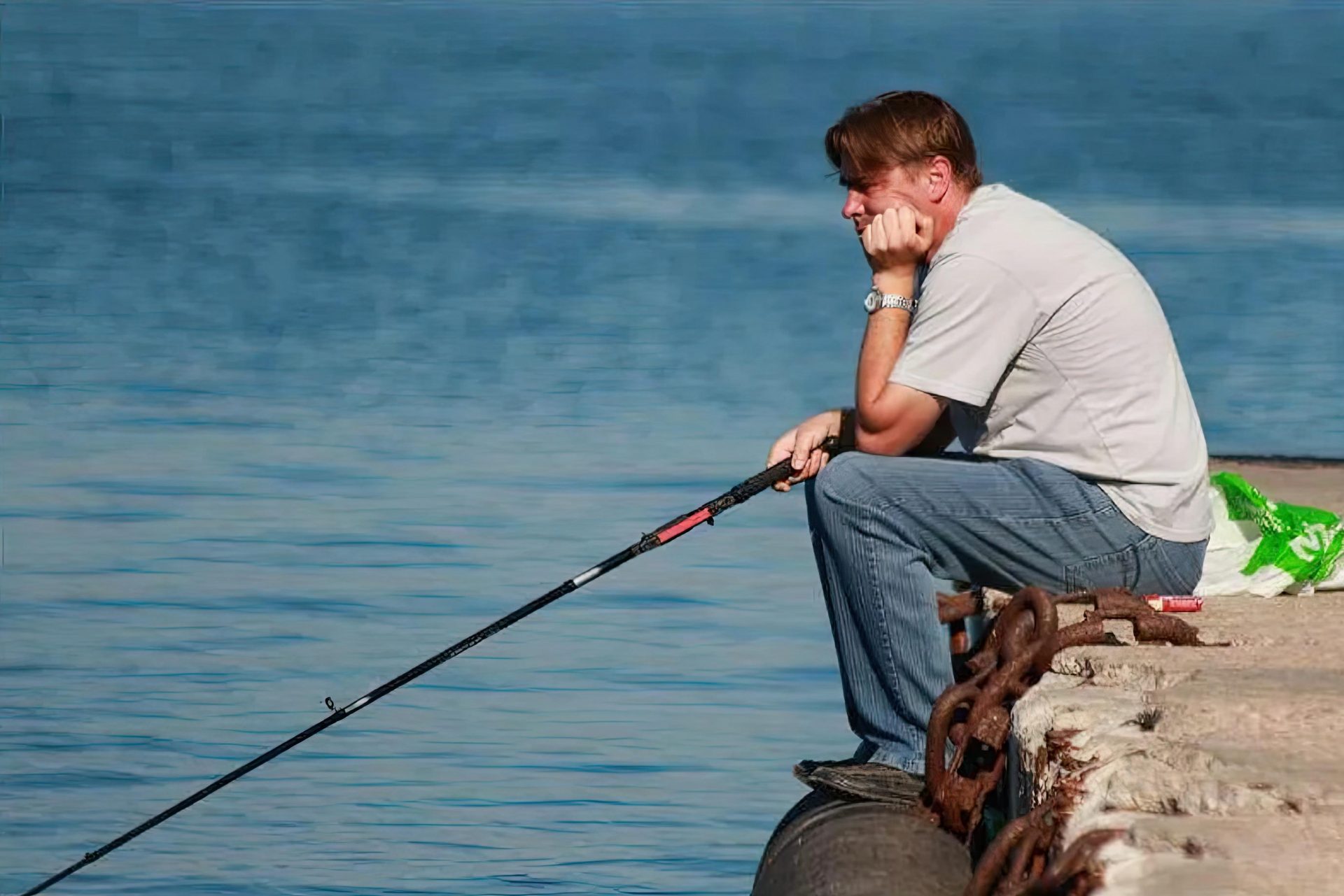 Веселый клев. Грустный Рыбак. Рыбак сидит. Человек рыбачит на берегу. Мужик с удочкой.